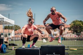 Une femme et un homme sautent sur un podium lors d'une séance de cross-training.